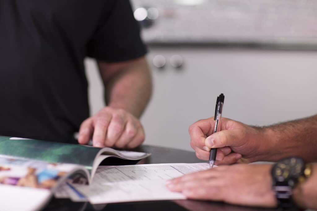Boat dealer customer signing paperwork.