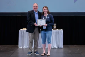 Angela Brayton receives the 2024 Kevin Lodder Scholarship on stage at an the annual MRAA awards luncheon at Dealer Week.