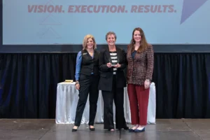 Nancy Cueroni receives the 2024 Darlene Briggs Marine Woman of the Year Award on stage the annual MRAA awards luncheon.