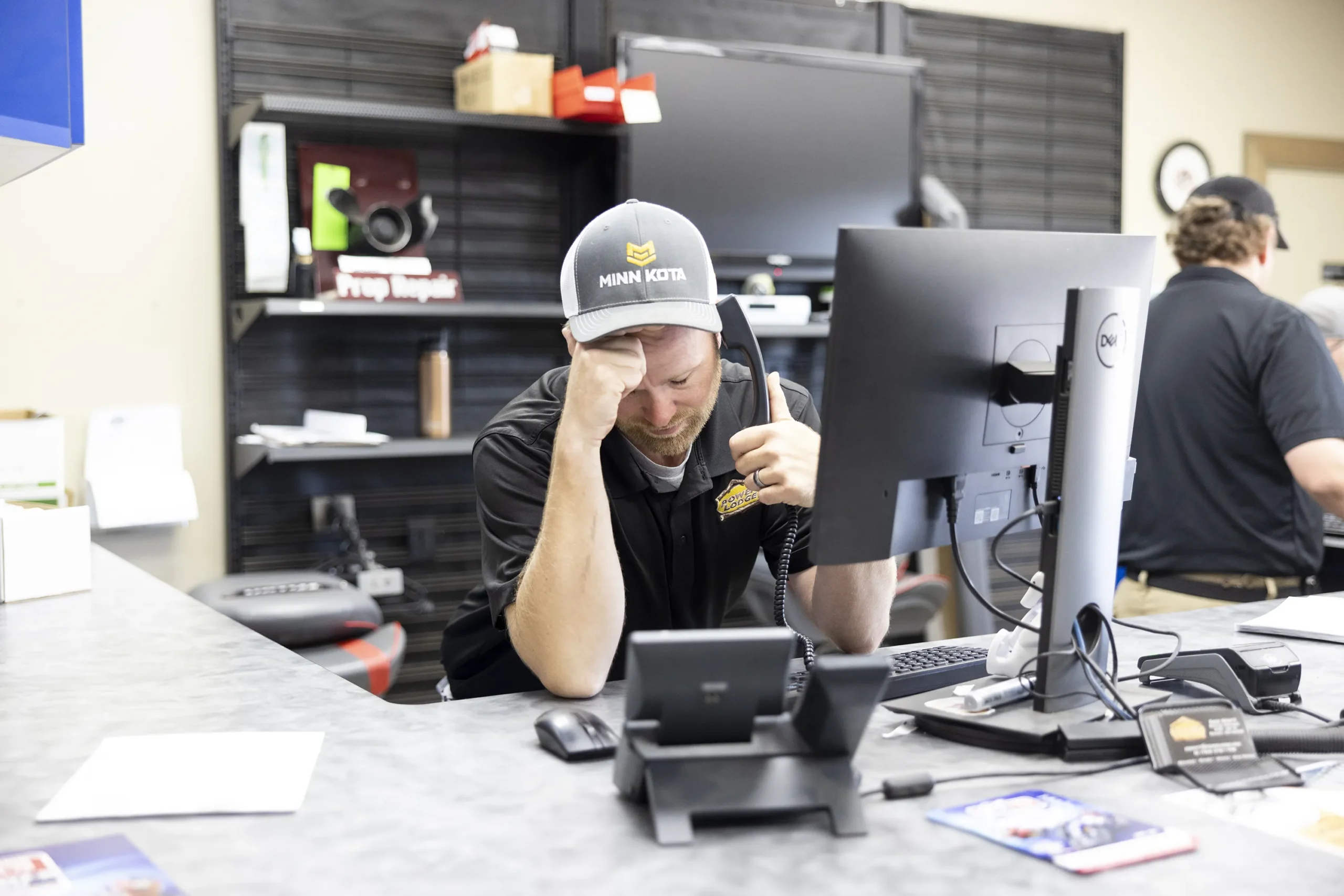A stressed out employee at a dealership rubbing his forehead in frustration.
