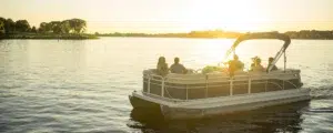 Boaters enjoying a pontoon boat on a calm lake at sunset, representing consumer lifestyle insights shaping the future of marine retail.