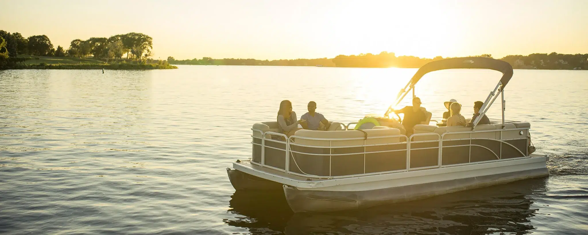 Boaters enjoying a pontoon boat on a calm lake at sunset, representing consumer lifestyle insights shaping the future of marine retail.