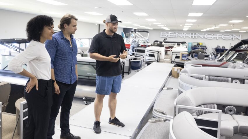 Sales person with shoppers in showroom at boat dealership.